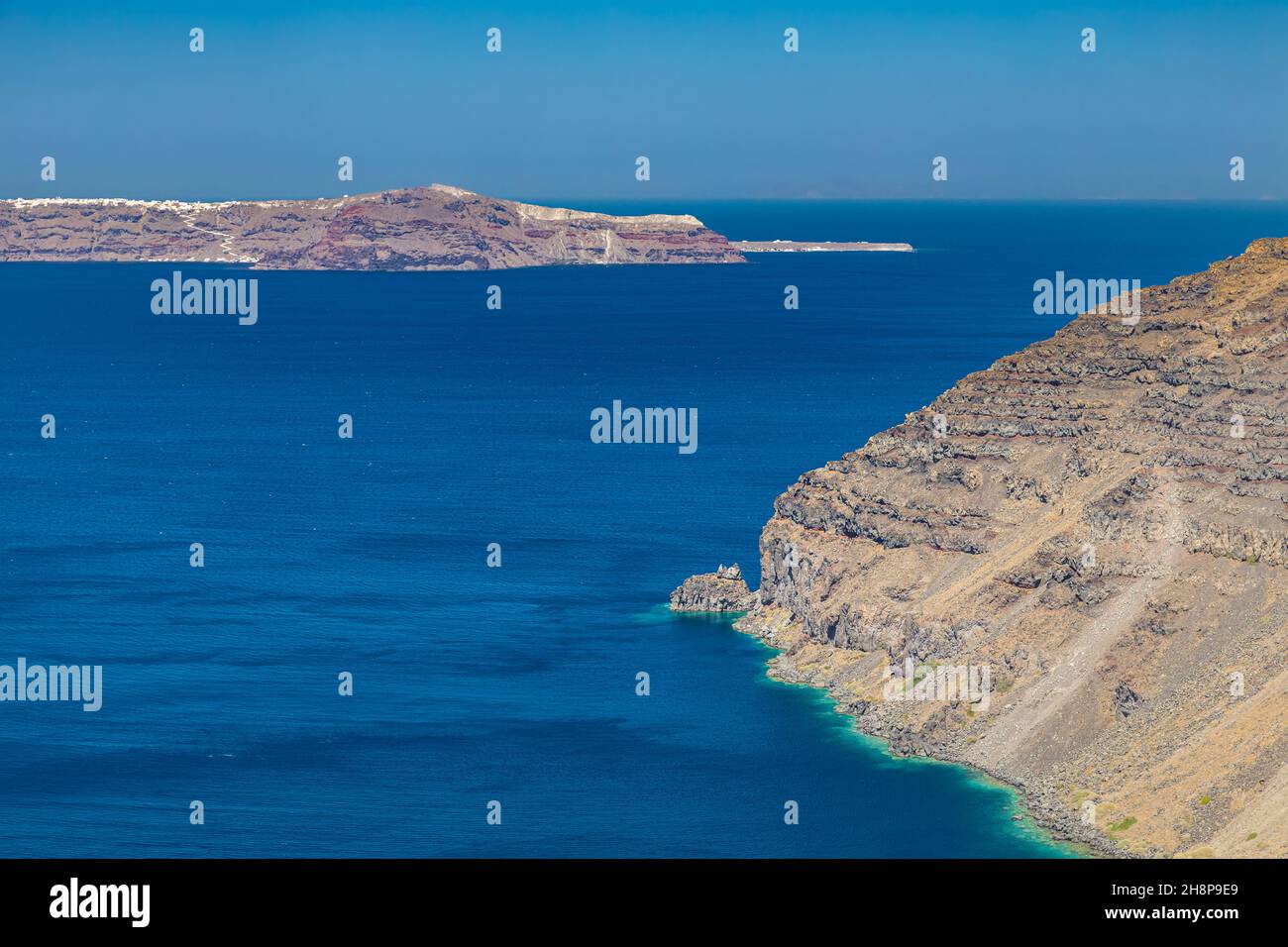 Parete scogliera dell'isola di Santorini, Grecia. Oceano blu chiaro, mare, con spazio di copia, posto per il testo. Shore, costa di rocce asciutte Foto Stock