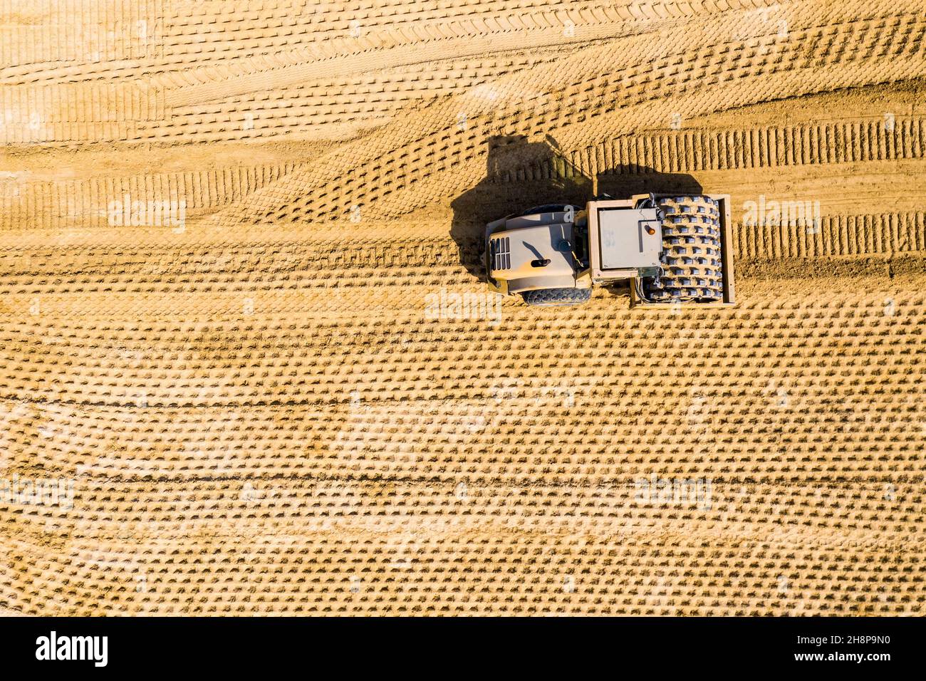 Foto aerea di un rullo a vapore e un retroescavatore su un lavori in corso Foto Stock