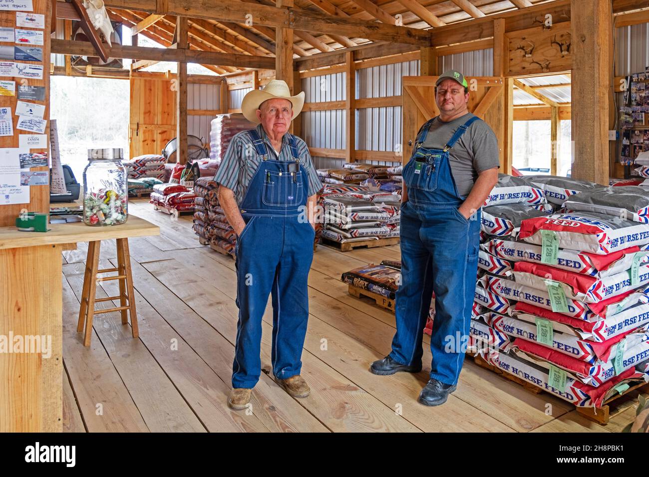 Due coltivatori texani che indossano salopette, tute e cappelli da cowboy nel negozio di mangimi a Bon Wier nella contea di Newton orientale, Texas, Stati Uniti / USA Foto Stock