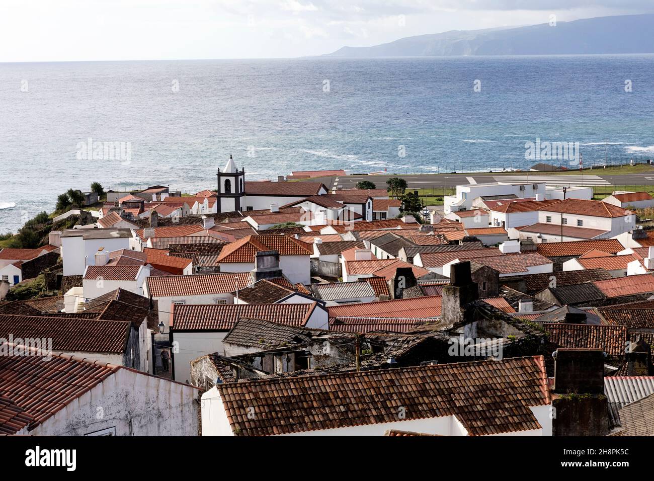 Vista dei tetti della costruzione di Vila do Corvo, pista aeroportuale e l'isola di Flores sullo sfondo, isola di Corvo Azzorre Portogallo Foto Stock
