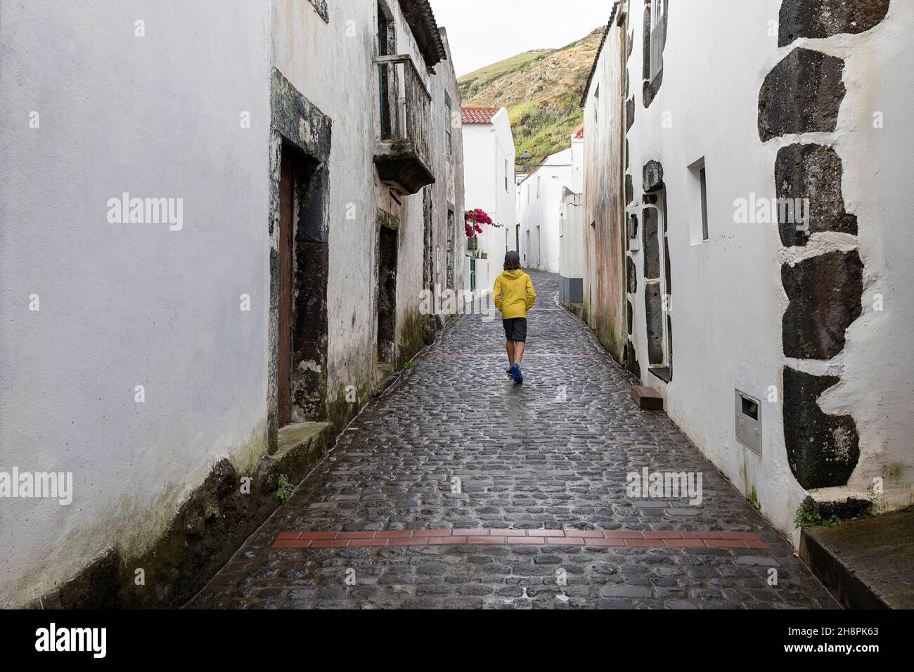 Ragazzo in giacca gialla che cammina per le strade di Vila do Corvo, isola Corvo Azzorre Portogallo Foto Stock