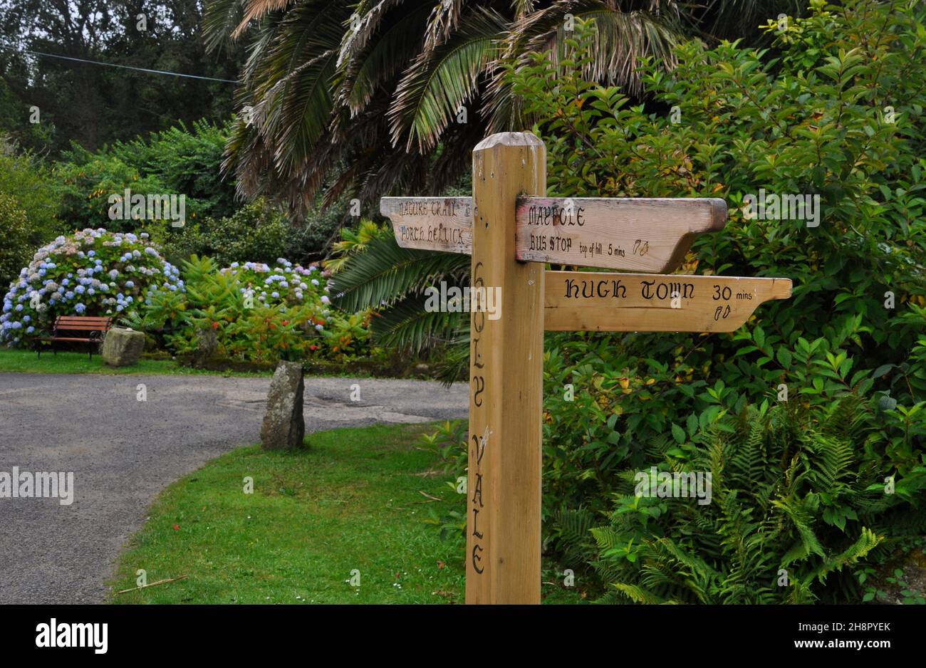 Il cartello in legno di Holy vale indica il tempo che ci vorrà per raggiungere a piedi vari luoghi dell'isola di St Marys nelle isole di Scilly, Cornwal Foto Stock