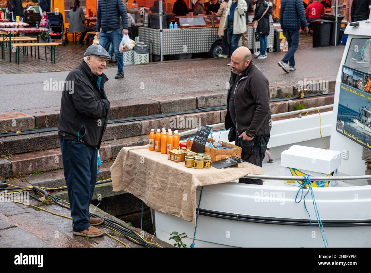 Uomo di mezza età che vende prodotti correlati al buckhorn marino da boat stall presso la Piazza del mercato di Helsinki, Finlandia Foto Stock