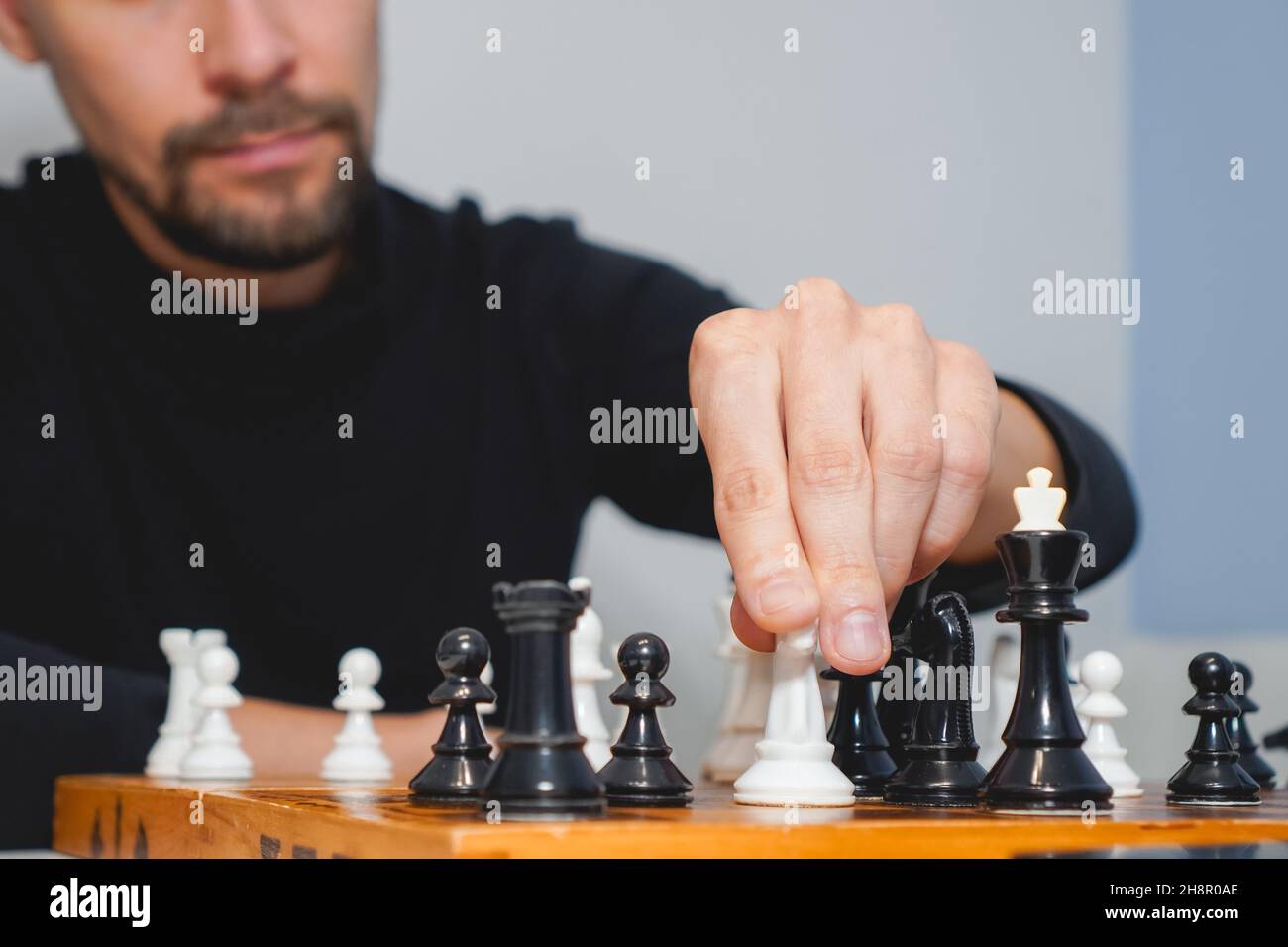 Uomo premuroso che indossa la barba e gioca a scacchi a bordo. Strategia e concetto di concorrenza. Messa a fuoco selettiva Foto Stock