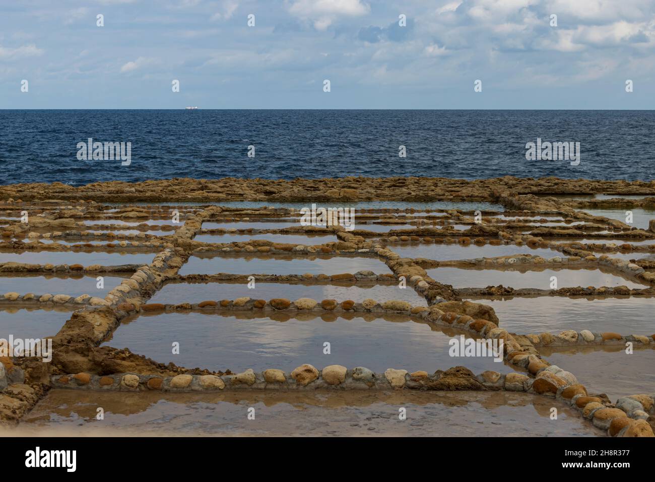 Paesaggio minimalista di saline a Gozo in una giornata nuvolosa con vista sul Mar Mediterraneo. Foto Stock