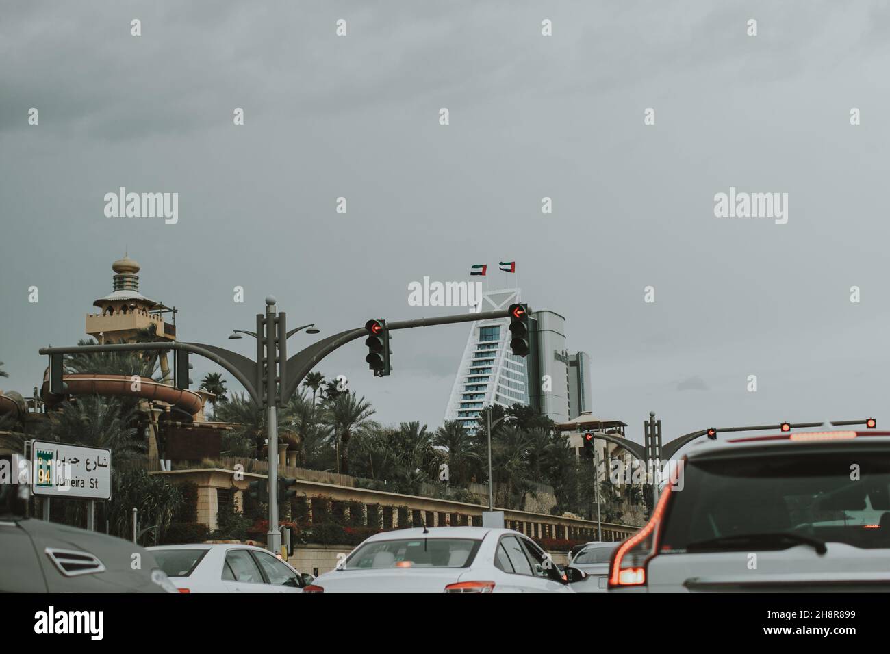 Traffico di auto su strada Jumeirah di Dubai con molte auto, tavole stradali di direzione, palme, semafori e oggetti turistici Foto Stock