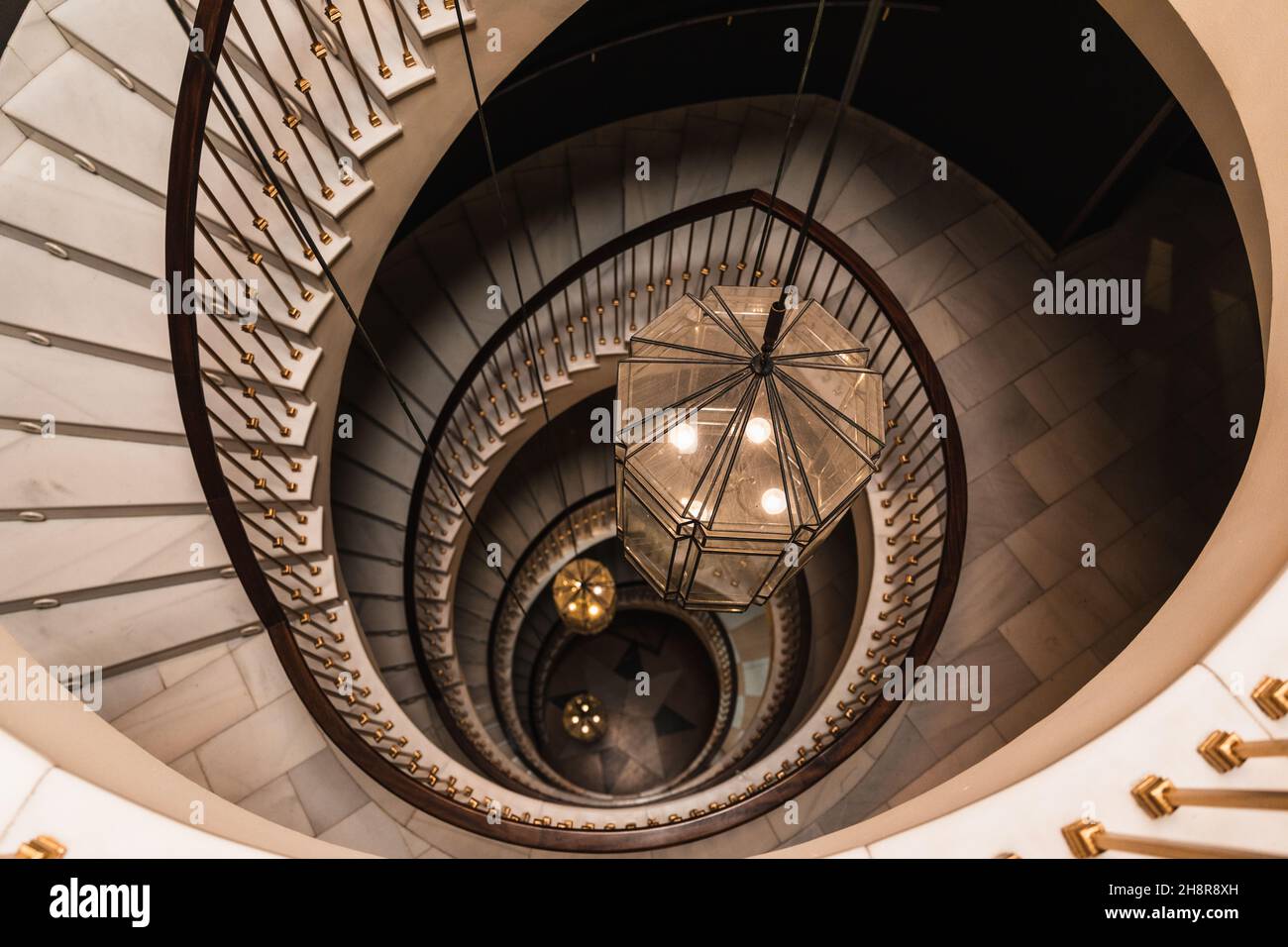 Foto dall'alto di una scala a chiocciola con tre grandi lampade in tonalità oro e marrone. Foto Stock