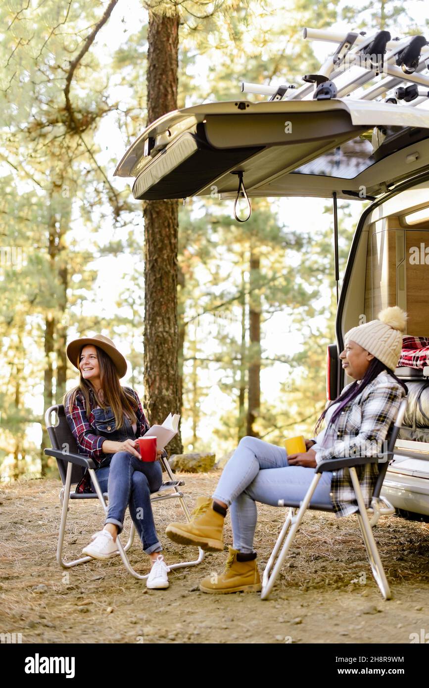 Diverse donne in viaggio vicino camper in boschi Foto Stock