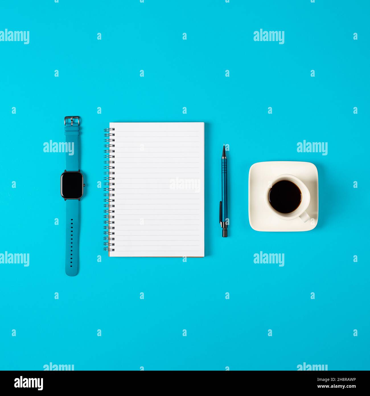 Blocco note, orologio, penna e una tazza di caffè isolato su sfondo blu. Blocco note con spazio di copia. Ufficio, lavoro, stile discreto Foto Stock