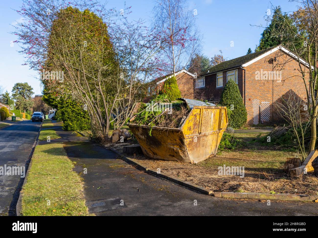 Un grande arrugginito, rifiuti di rifiuti martoriati saltare pieno di rami e rifiuti di giardino sul giardino di fronte di una strada a Surrey, nel sud-est dell'Inghilterra Foto Stock