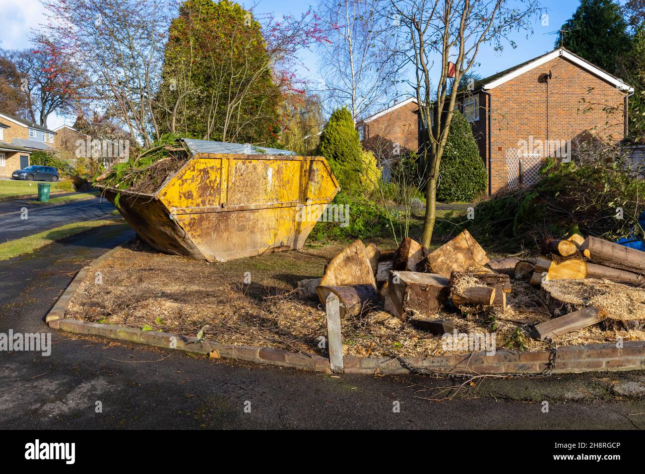 Un grande arrugginito, rifiuti di rifiuti martoriati saltare pieno di rami e rifiuti di giardino sul giardino di fronte di una strada a Surrey, nel sud-est dell'Inghilterra Foto Stock