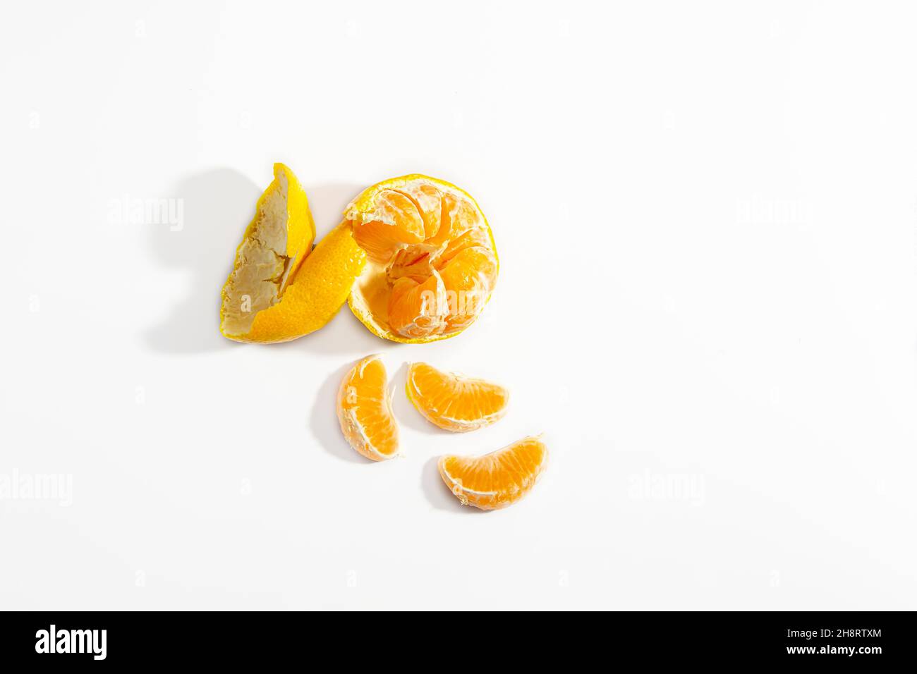 Mandarino semipello e tre spicchi di mandarino su sfondo bianco. Isolare. Stile di vita. Clos ap. Foto orizzontale. Foto di alta qualità Foto Stock