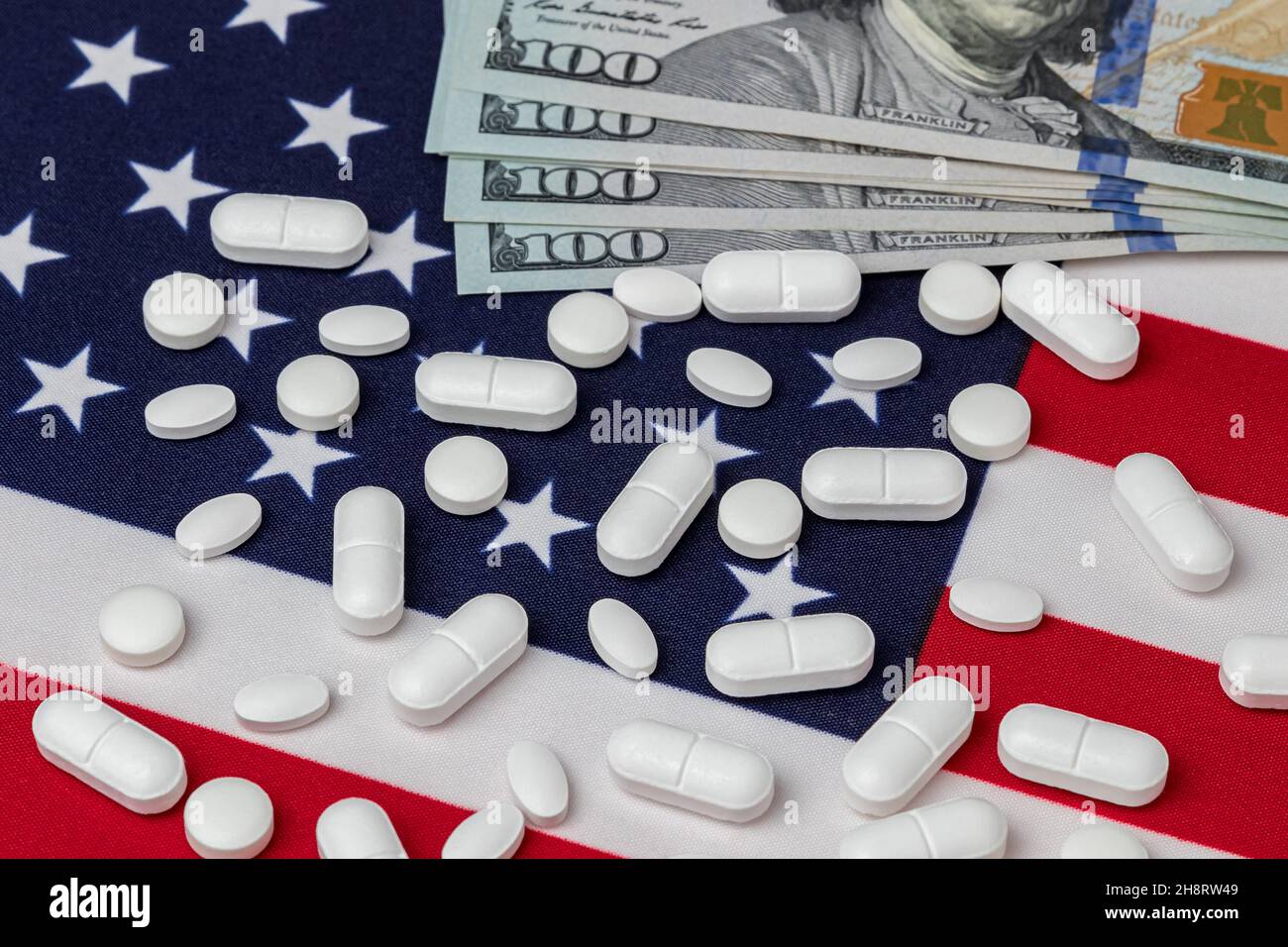 Pillole di medicina di prescrizione e fatture di 100 dollari sulla bandiera americana. Industria farmaceutica, importazioni ed esportazioni, e costi di dipendenza da oppioidi antidolorifici Foto Stock