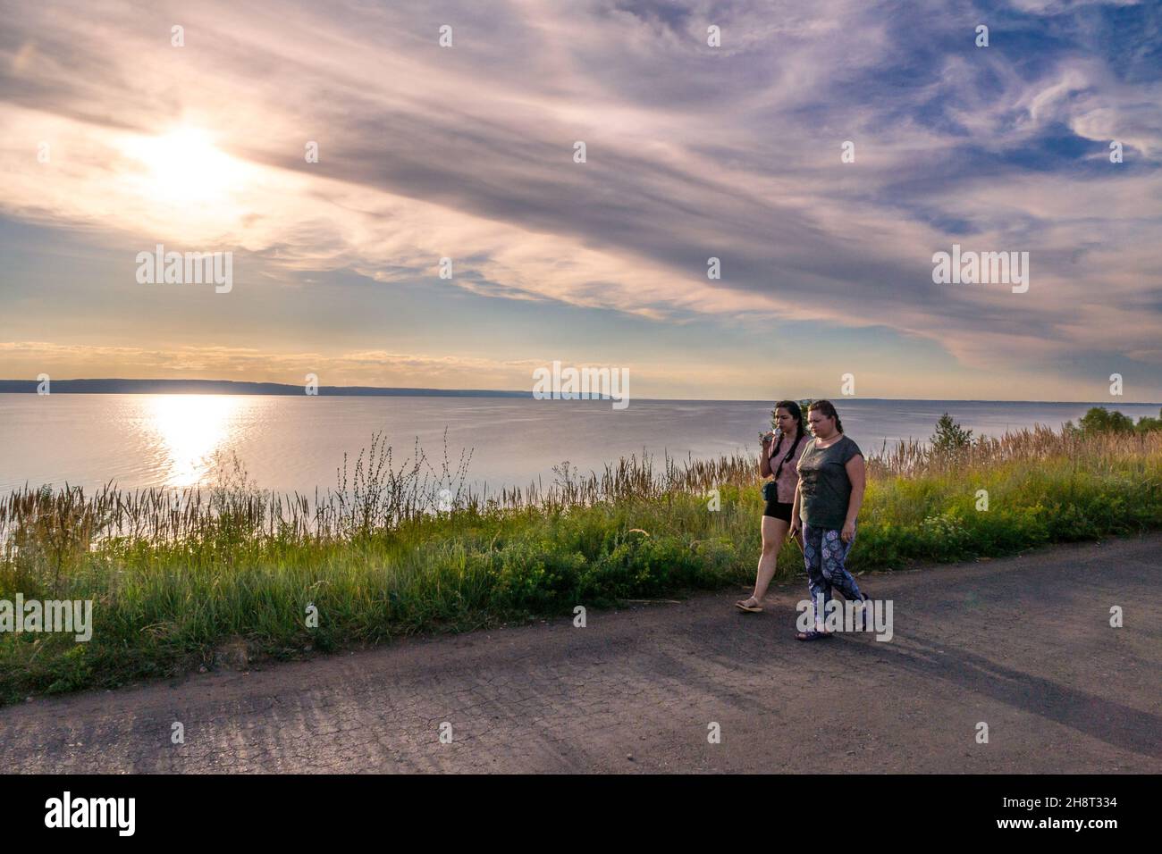 Khryashchevka (Russia), 16 luglio 2020, due donne positive per il corpo in una passeggiata serale che parlano e camminano lungo un sentiero lungo la riva di un lago o di un fiume, Foto Stock