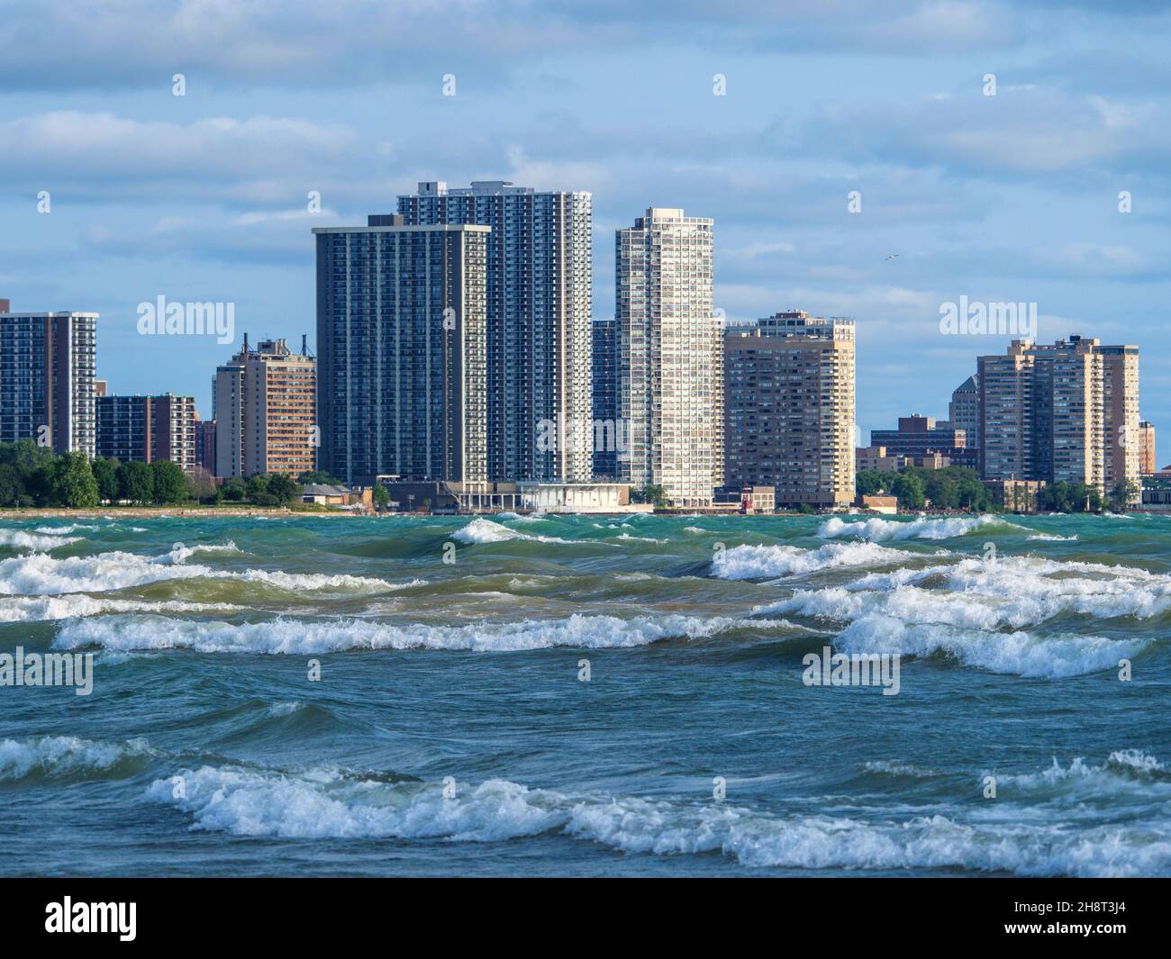 High surf a Montrose Beach di Chicago con gli alti appartamenti del quartiere Edgewater sullo sfondo. Foto Stock