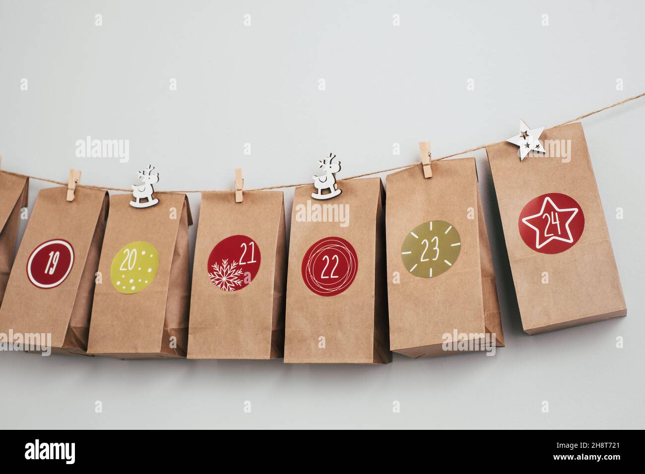 Calendario dell'avvento di Natale sospeso sul muro. Borse artigianali fatte a mano con regali e compiti per i bambini. Conto alla rovescia per la vigilia di Natale, in attesa del miracolo Foto Stock