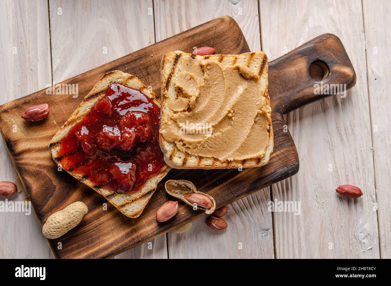 Vista su una superficie piana del burro di arachidi e dei sandwich di marmellata sul tagliere. Concetto di cibo sano Foto Stock