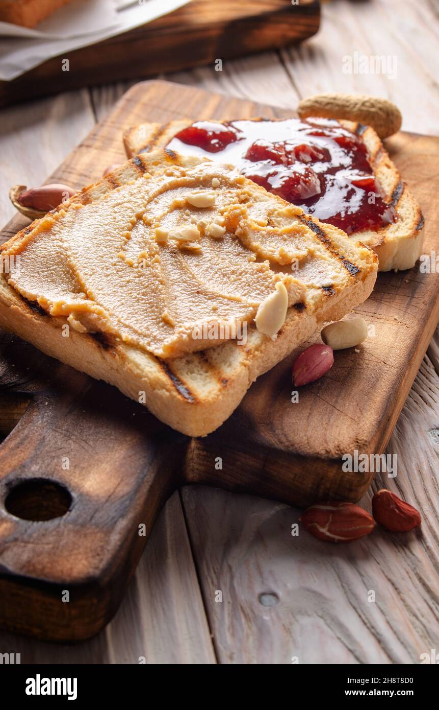 Vista dal primo piano ad angolo basso al burro di arachidi e sandwich di marmellata sul tagliere. Concetto di cibo sano Foto Stock