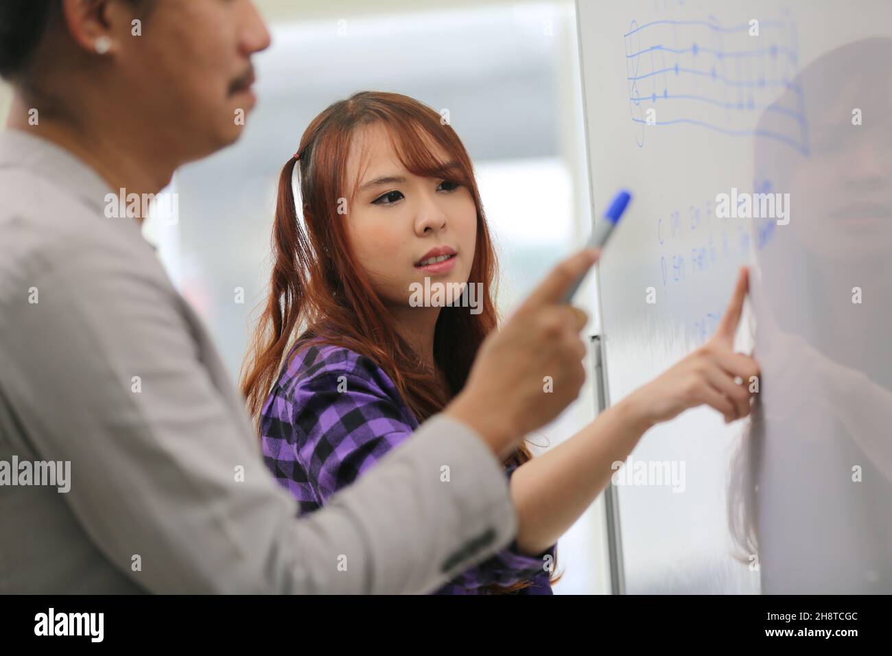 Tutor con giovane ragazza allegra insegnamento suona nota fonetica sulla lavagna. Foto Stock