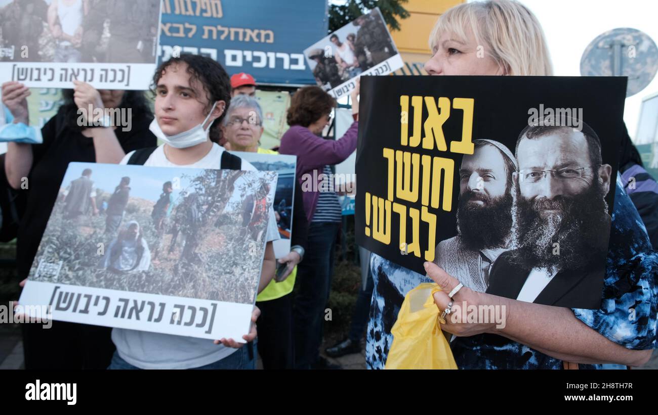 Gli attivisti di sinistra israeliani e i sostenitori del movimento Peace Now hanno dei segnali che mostrano foto di soldati israeliani con una scritta che recita "questo è l'aspetto dell'occupazione” e un segno con l'immagine dell'assassino di massa Baruch Goldstein durante una manifestazione contro la visita del presidente israeliano Isaac Herzog al Moschea Ibrahimi, a cui gli ebrei si riferiscono come la Grotta di Machpelah, all'ingresso dell'insediamento israeliano di Kiryat Arba vicino alla città palestinese di Hebron in Cisgiordania, Israele. Foto Stock