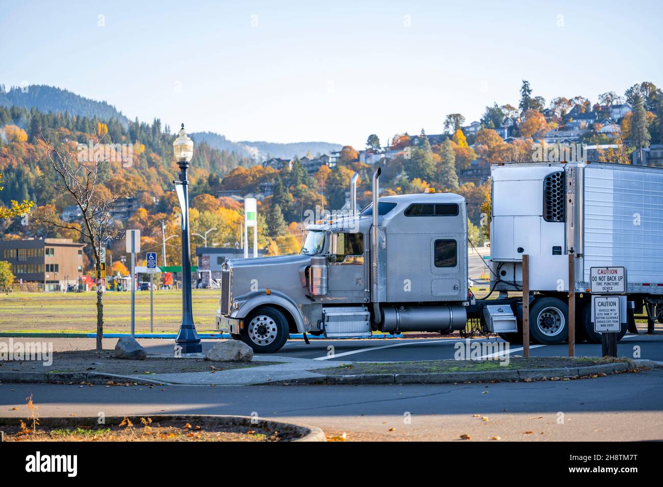 Industriale potente carro grigio grande classico semi-camion trasporto carico commerciale congelato in frigorifero semi-rimorchio che gira sulla strada della città con Foto Stock