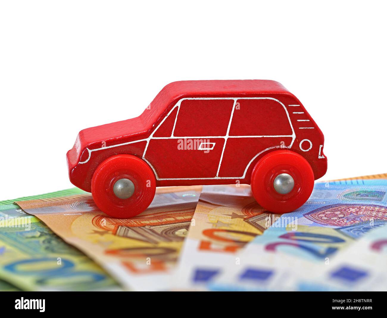 auto giocattolo in legno rosso su banconote in euro isolate su sfondo bianco con spazio per le copie Foto Stock