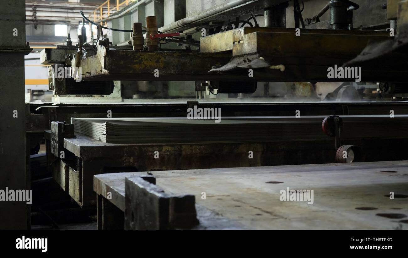 Impianto per la produzione di legno compensato. Macchine automatiche di officina di pressatura, strati pieghevoli di legno l'uno sull'altro. Foto Stock