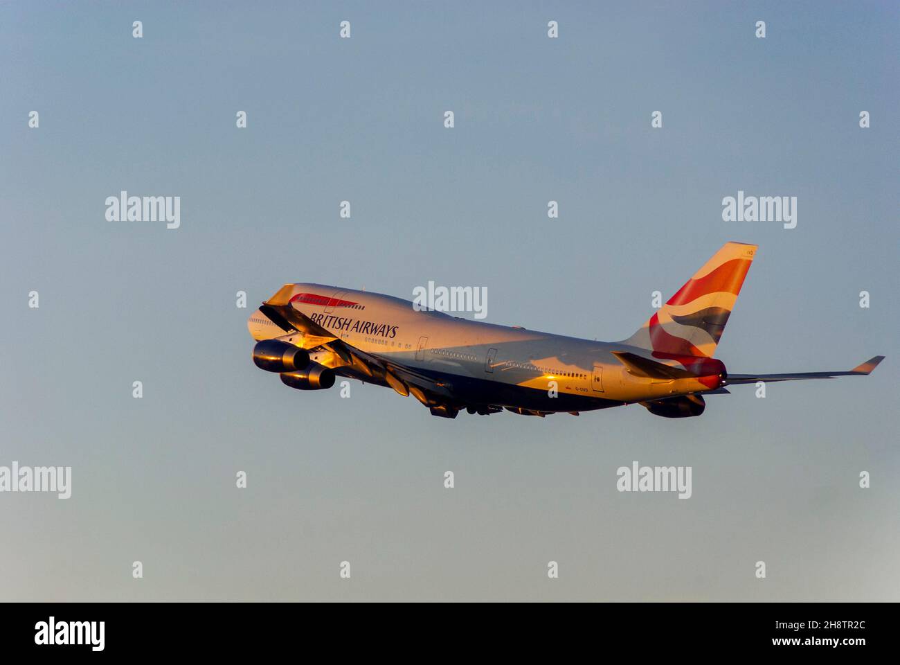 British Airways Boeing 747 Jumbo Jet aereo jet climbing dopo il decollo dall'aeroporto di Londra Heathrow, Regno Unito, al crepuscolo con caldo bagliore dal tramonto Foto Stock