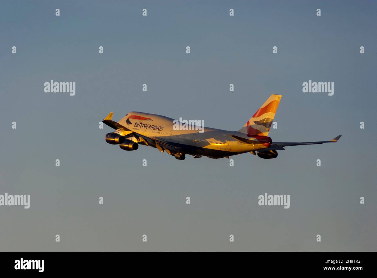 British Airways Boeing 747 Jumbo Jet aereo jet climbing dopo il decollo dall'aeroporto di Londra Heathrow, Regno Unito, al crepuscolo con caldo bagliore dal tramonto Foto Stock