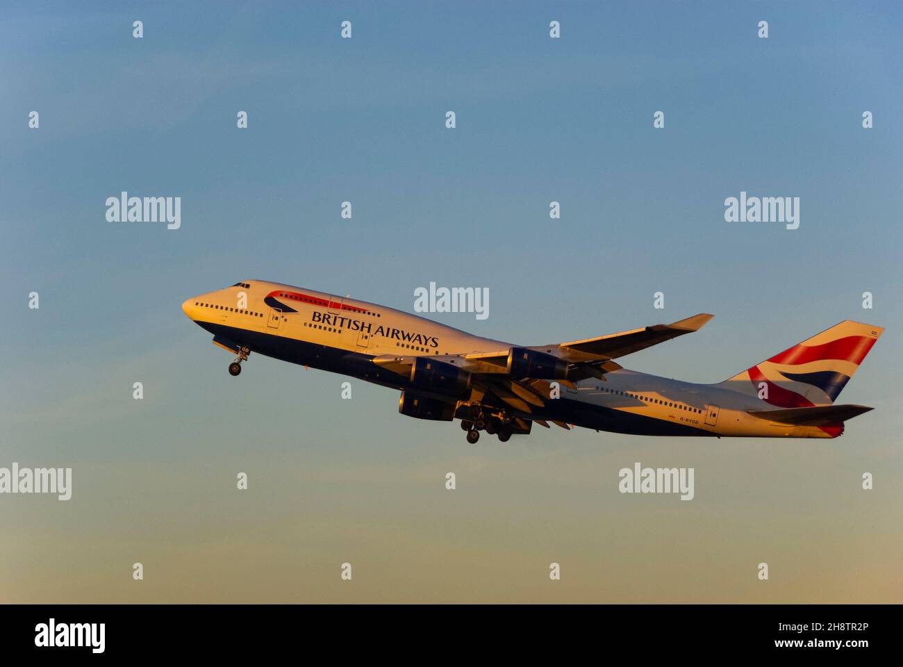 British Airways Boeing 747 Jumbo Jet aereo jet climbing dopo il decollo dall'aeroporto di Londra Heathrow, Regno Unito, al crepuscolo con caldo bagliore dal tramonto Foto Stock