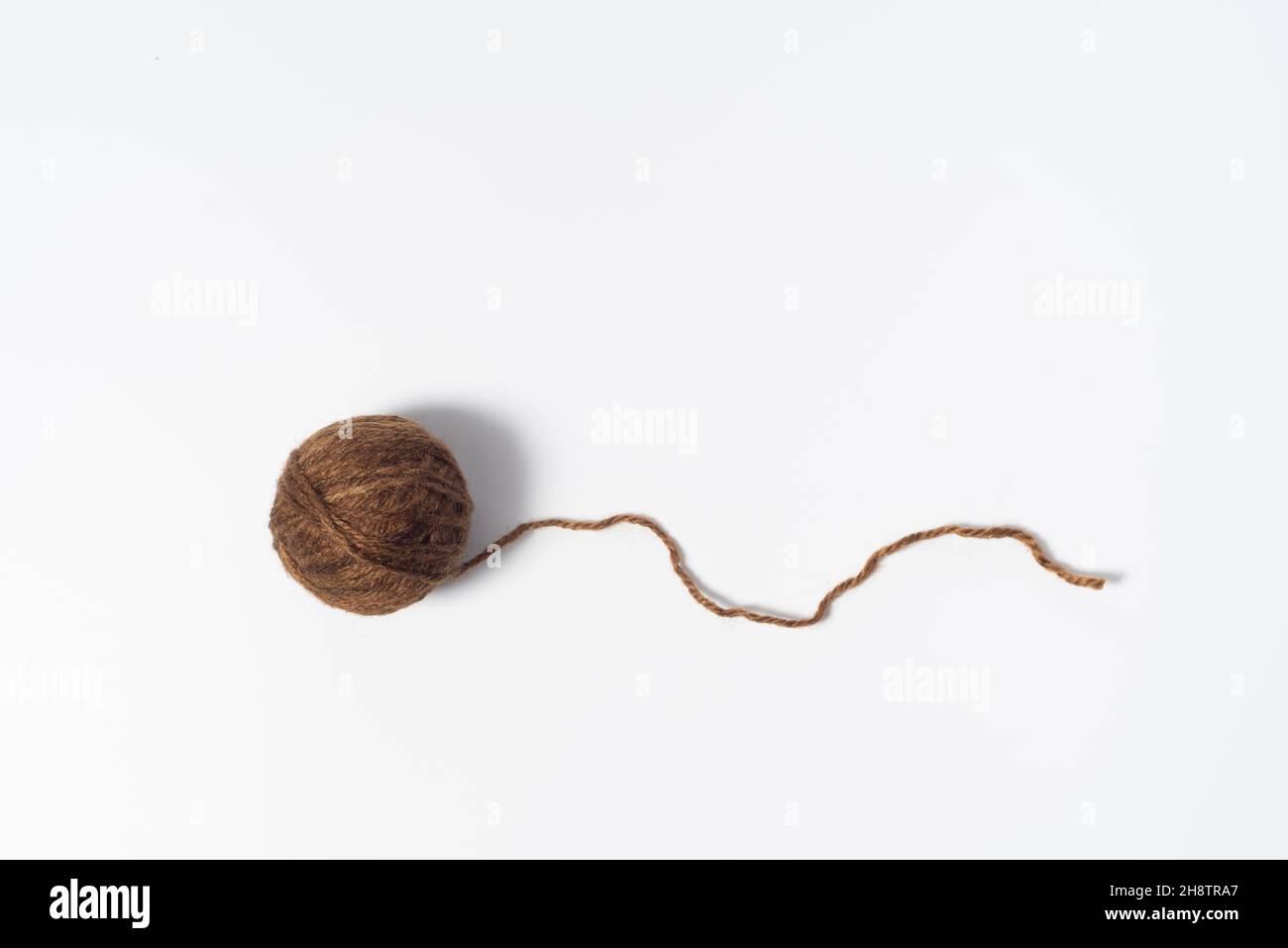 Sfera di filo marrone scuro con filo sciolto su fondo bianco Foto Stock