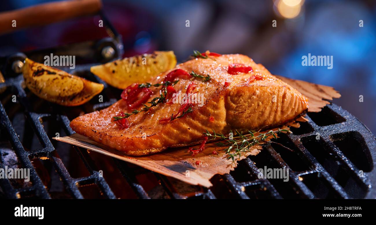 Fettine di filetto di salmone appetitoso con spezie ed erbe preparate con pezzi di limone su BBQ Grill Foto Stock