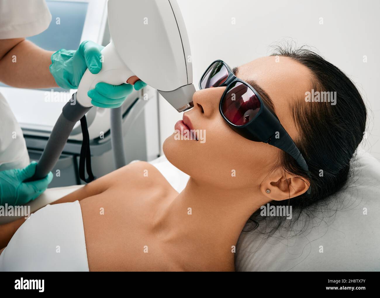 Bella donna che ha la rimozione dei capelli laser e l'epilazione laser a zona delle labbra sul suo viso al salone di cosmetologia Foto Stock