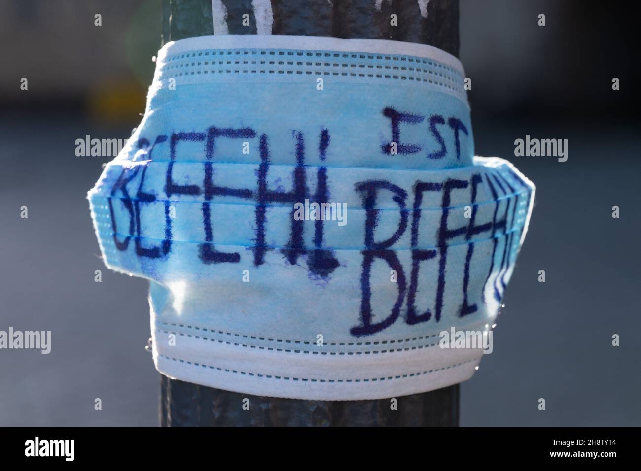 Dresda, Germania. 2 dicembre 2021. Un protettore medico bocca-naso con l'iscrizione 'Befehl ist Befehl' (ordini sono ordini) è appeso ad un lampione su Schlossplatz. Nonostante i valori di incidenza leggermente diminuiti, la Sassonia rimane di gran lunga il punto di riferimento della corona in Germania, secondo i dati del Robert Koch Institute (RKI). Credit: Kahnert/dpa-Zentralbild/dpa/Alamy Live News Foto Stock