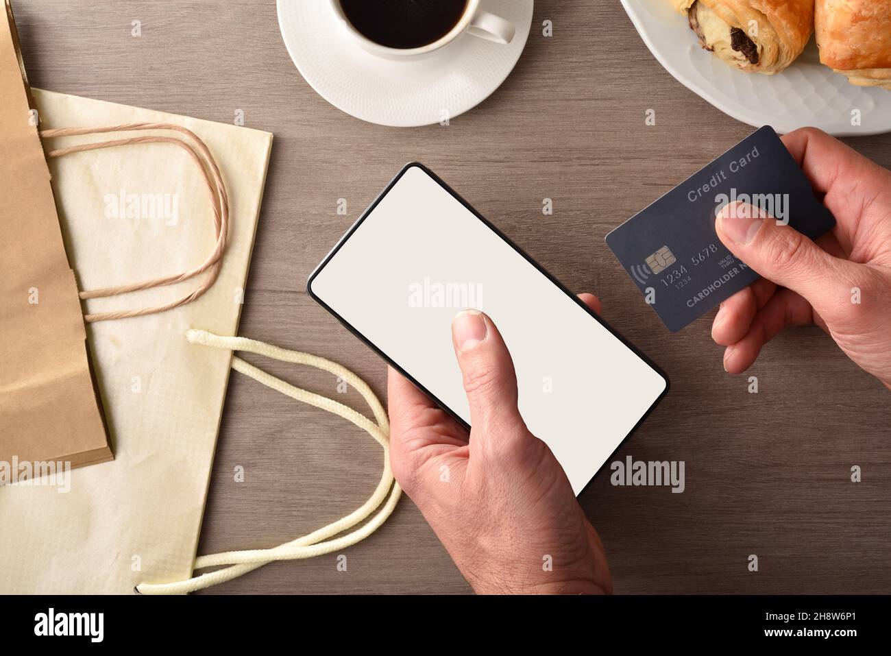 Fare un acquisto di Internet da casa da uno smartphone sulla panca della cucina con la prima colazione. Vista dall'alto. Composizione orizzontale. Foto Stock