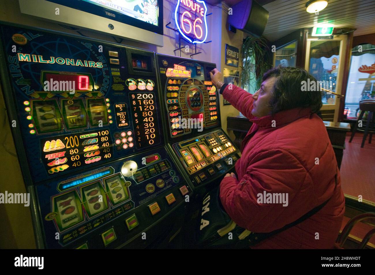 Amsterdam, Paesi Bassi. Adulto, maschio caucasico intorno ai suoi anni 50 visitando un caffè, sperando che la slot machine farà un pagamento questa volta. Una dipendenza dal gioco d'azzardo spesso costa un sacco di soldi, riversando la gente nel debito. È un disturbo psicologico che può essere trattato. Foto Stock