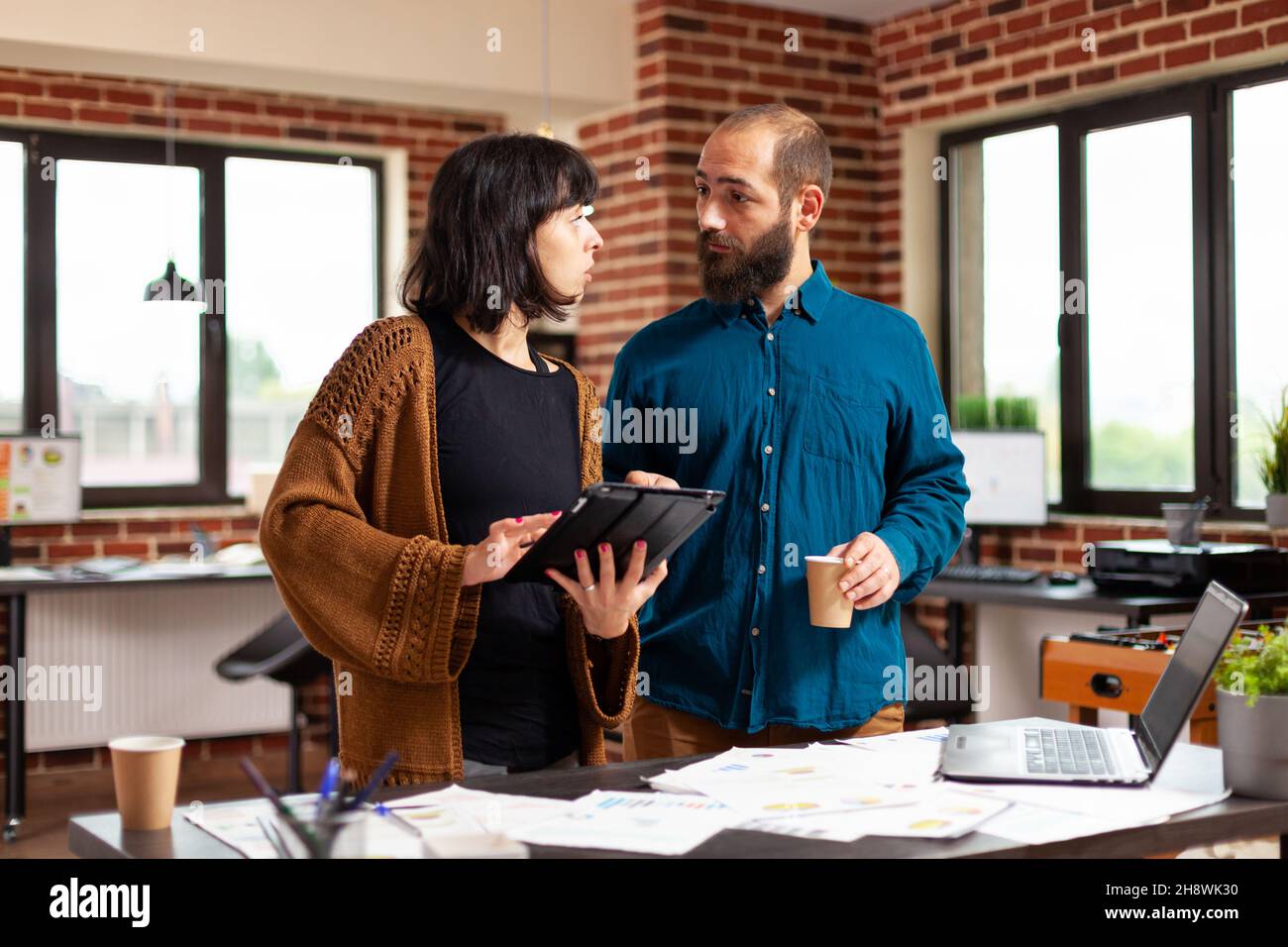 Donna d'affari che tiene il computer tablet che mostra il rapporto di affari al collega uomo che discute la strategia dell'azienda nell'ufficio di startup. Businessspeople idee di brainstorming che lavorano alla presentazione di vendita Foto Stock