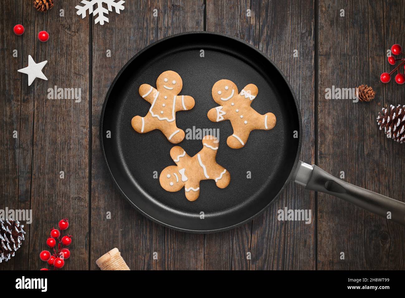 Cottura di biscotti di Natale in un concetto di padella. Preparazione natalizia in cucina con decorazioni. Vista dall'alto, composizione piatta su scrivania in legno Foto Stock