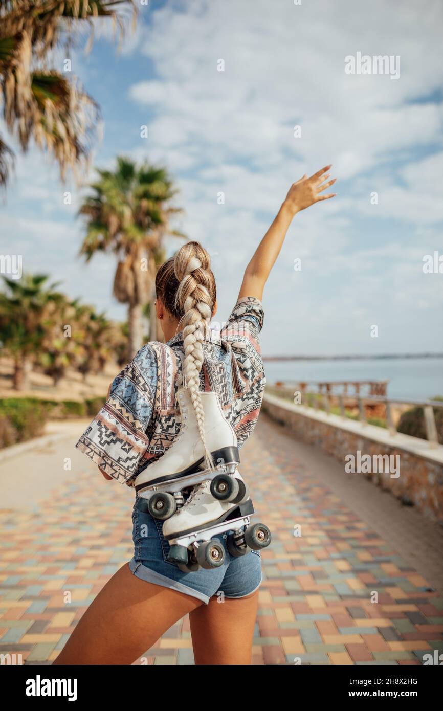 Femmina sorridente in giacca e dolcevita con occhiali VR vicino alle finestre dell'edificio in luce del giorno Foto Stock