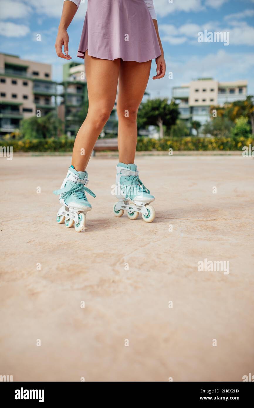 Crop anonimo sportivo femminile in turchese pattini a rotelle in piedi sul  passaggio pedonale su strada con edifici e alberi durante l'allenamento  Foto stock - Alamy