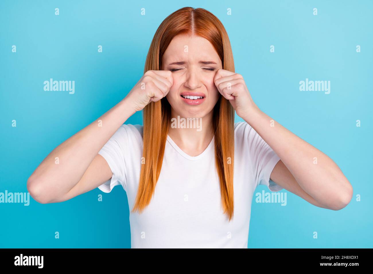 Ritratto di capelli arancioni insoddisfatti giovane ragazza braccia sotto gli occhi gridando isolato su sfondo di colore blu pastello Foto Stock