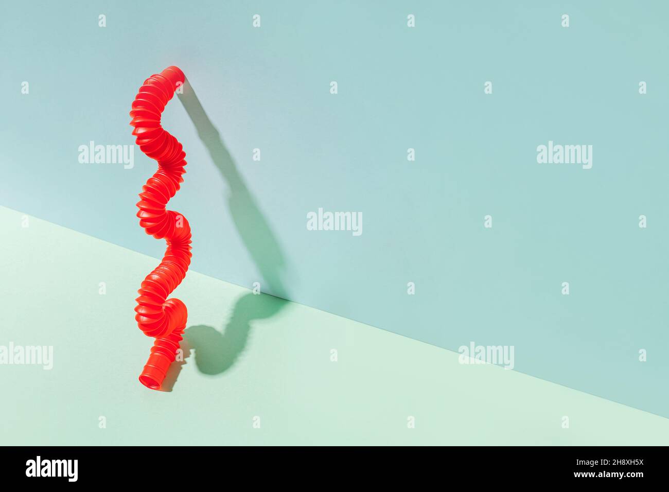 Il tubo pop curvo è appoggiato contro la parete. Vita morta moderna con giocattolo antistress. Foto Stock