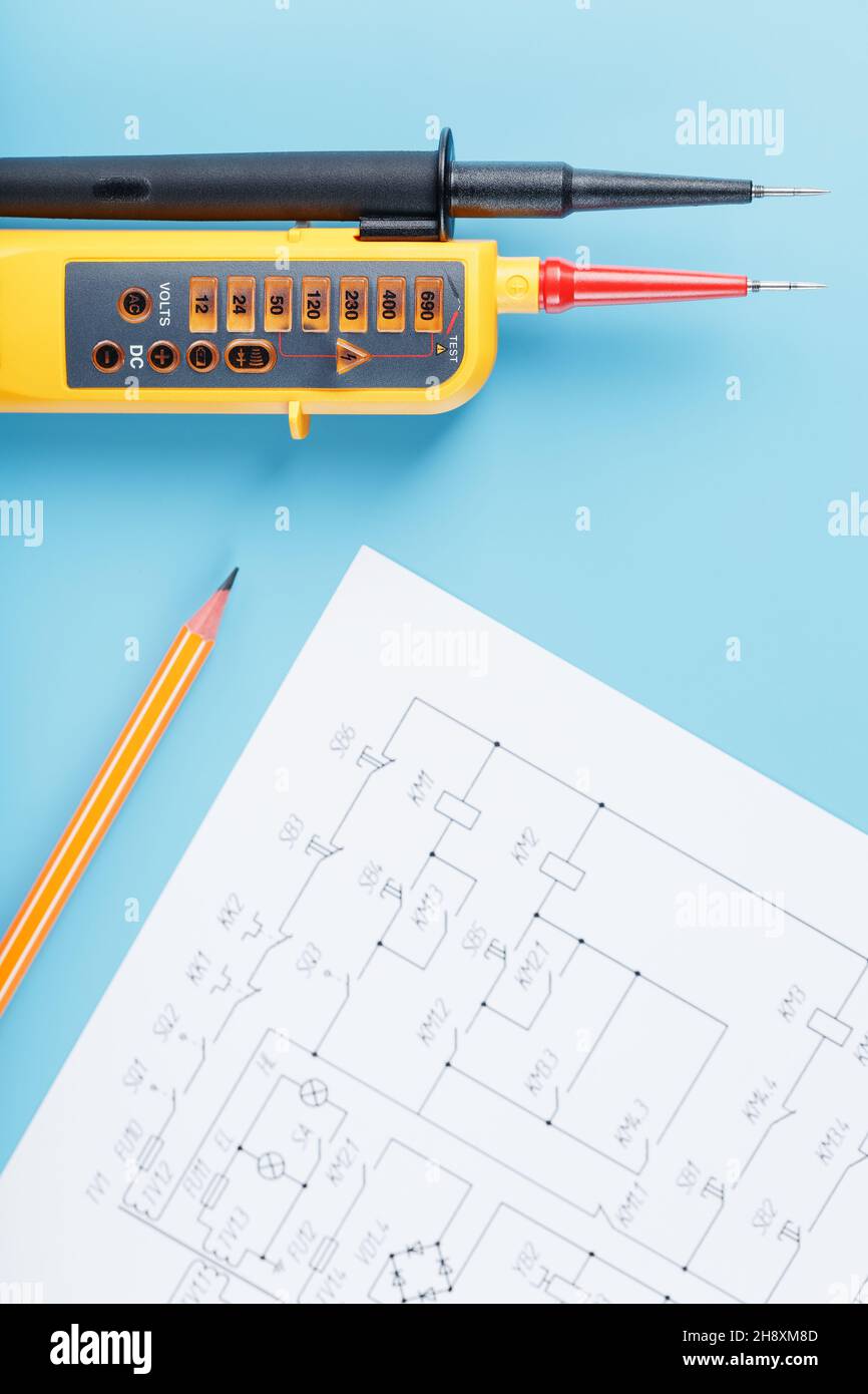Indicatore di tensione giallo con uno schema elettrico su sfondo blu. Test e verifica delle reti elettriche Foto Stock
