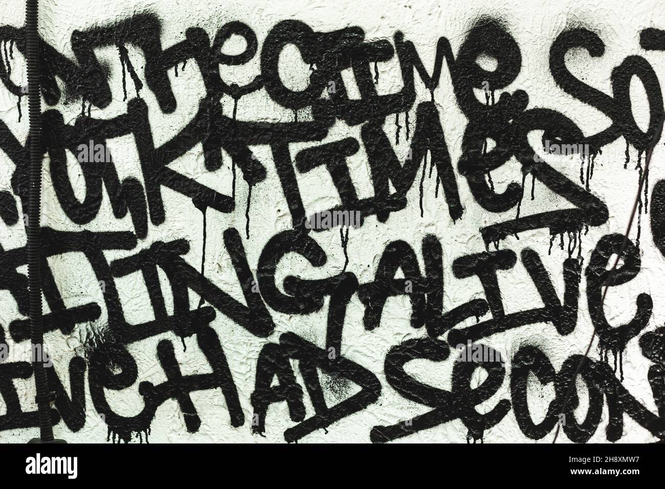 Graffiti in bianco e nero che disegnano da parole casuali in un bel carattere sulla parete come decorazione o decorazione Foto Stock
