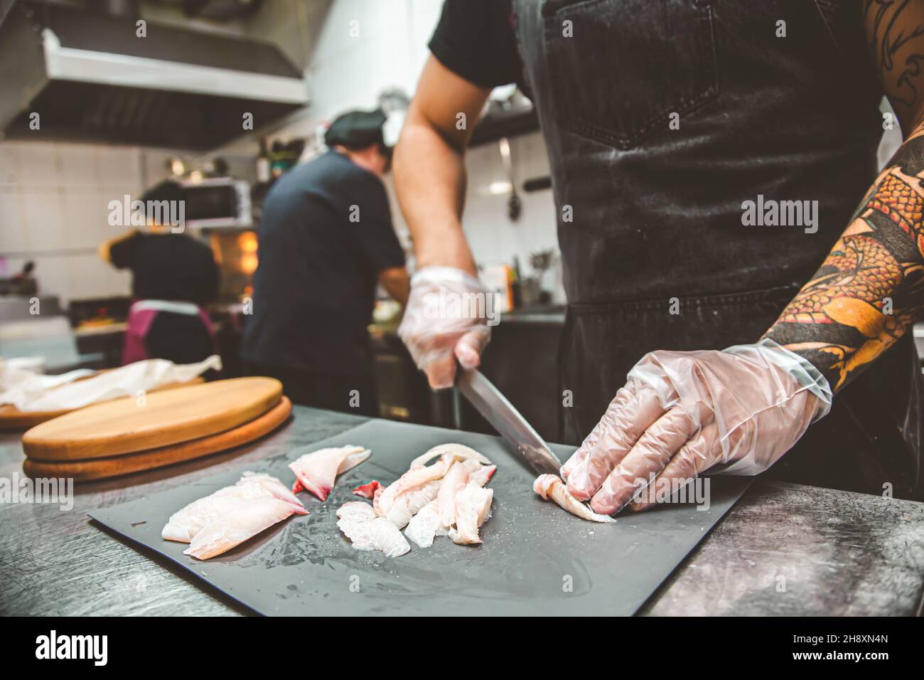 uno chef in un ristorante taglia il pesce per preparare il sushi Foto Stock