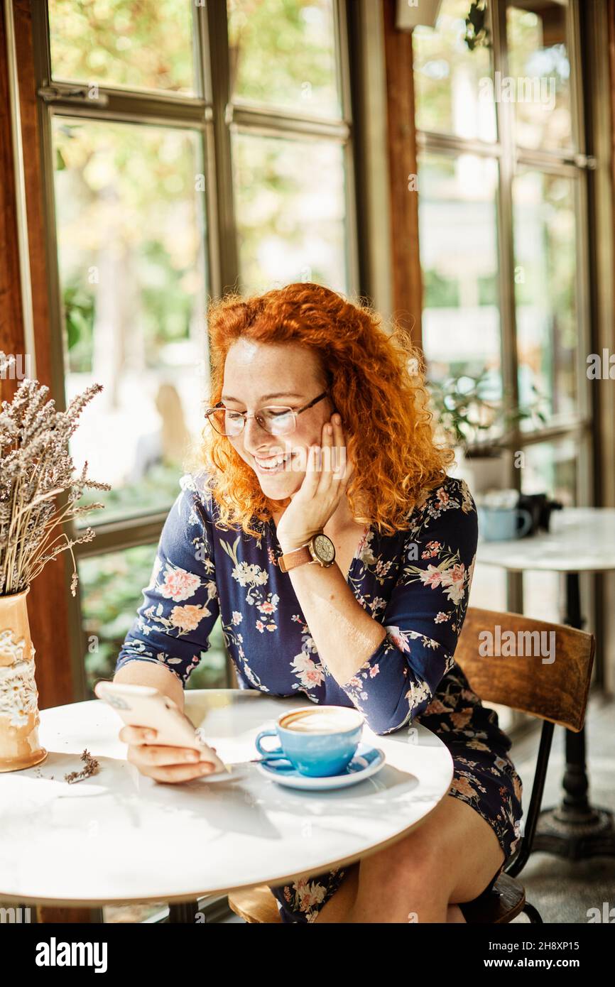 cafe donna ragazza lifestyle bere caffè giovane smartphone comunicazione utilizzando bello sorridente felice femmina Foto Stock