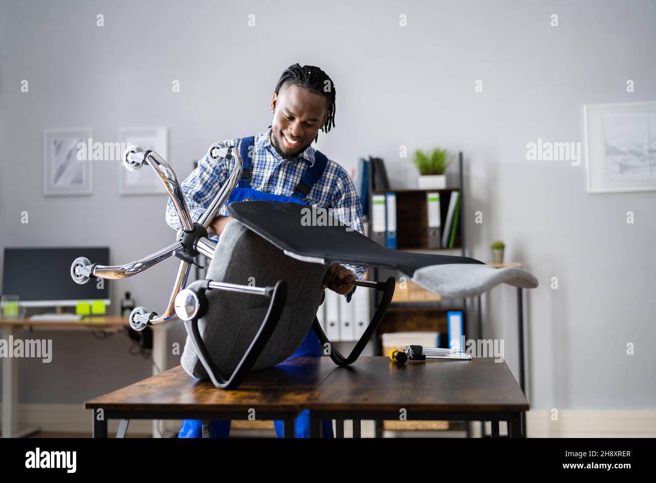Assemblaggio e riparazione della sedia da ufficio. Uomo che lavora con lo strumento Foto Stock