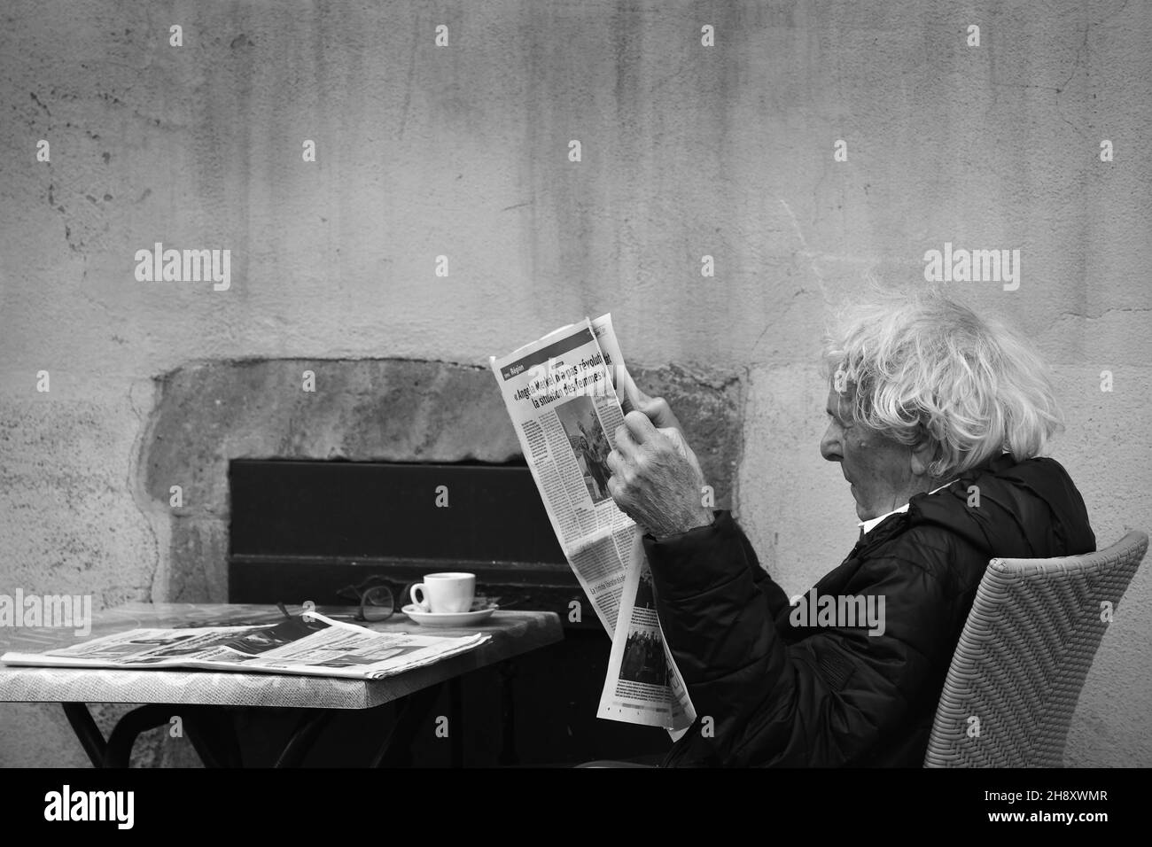 Man Reading giornale all'aperto bar ristorante a Colmar, Francia Foto Stock
