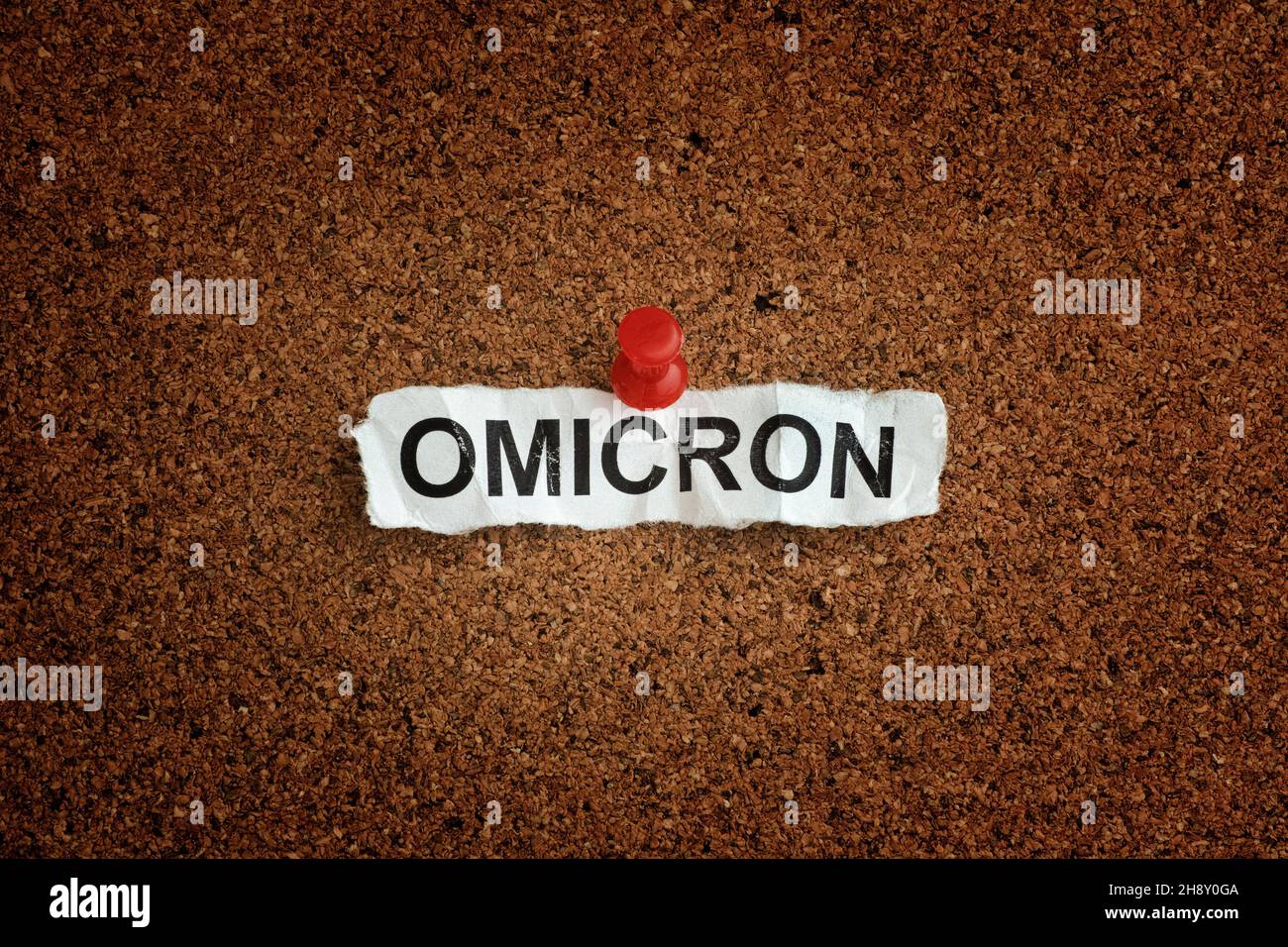 La parola Omicron su un pezzo di carta che è fissato a un asse di sughero. Variante Omicron di COVID-19. Primo piano. Foto Stock