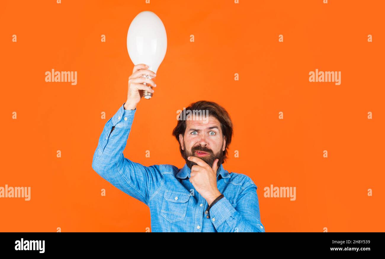 Buona idea. Uomo pensante con lampadina. Innovazione e ispirazione. Maschio bearded con lampada in mano. Foto Stock